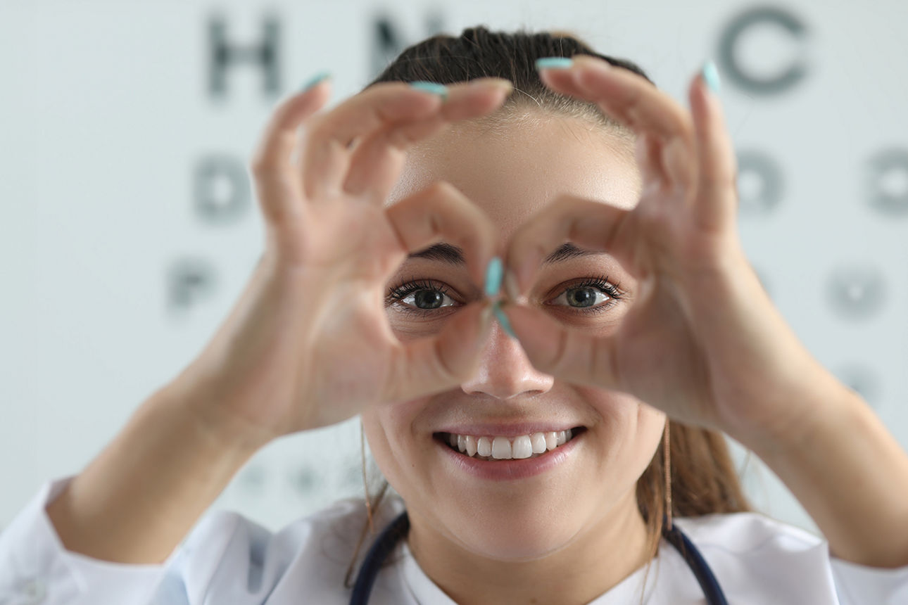 junge Frau beim Optiker formt Brille mit den Händen