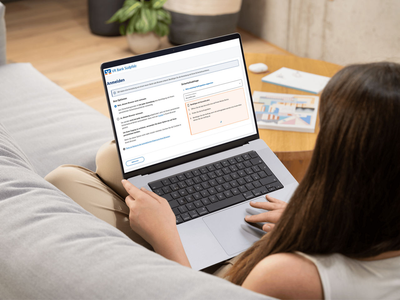 Frau sitzt auf dem Sofa und loggt sich im OnlineBanking ein
