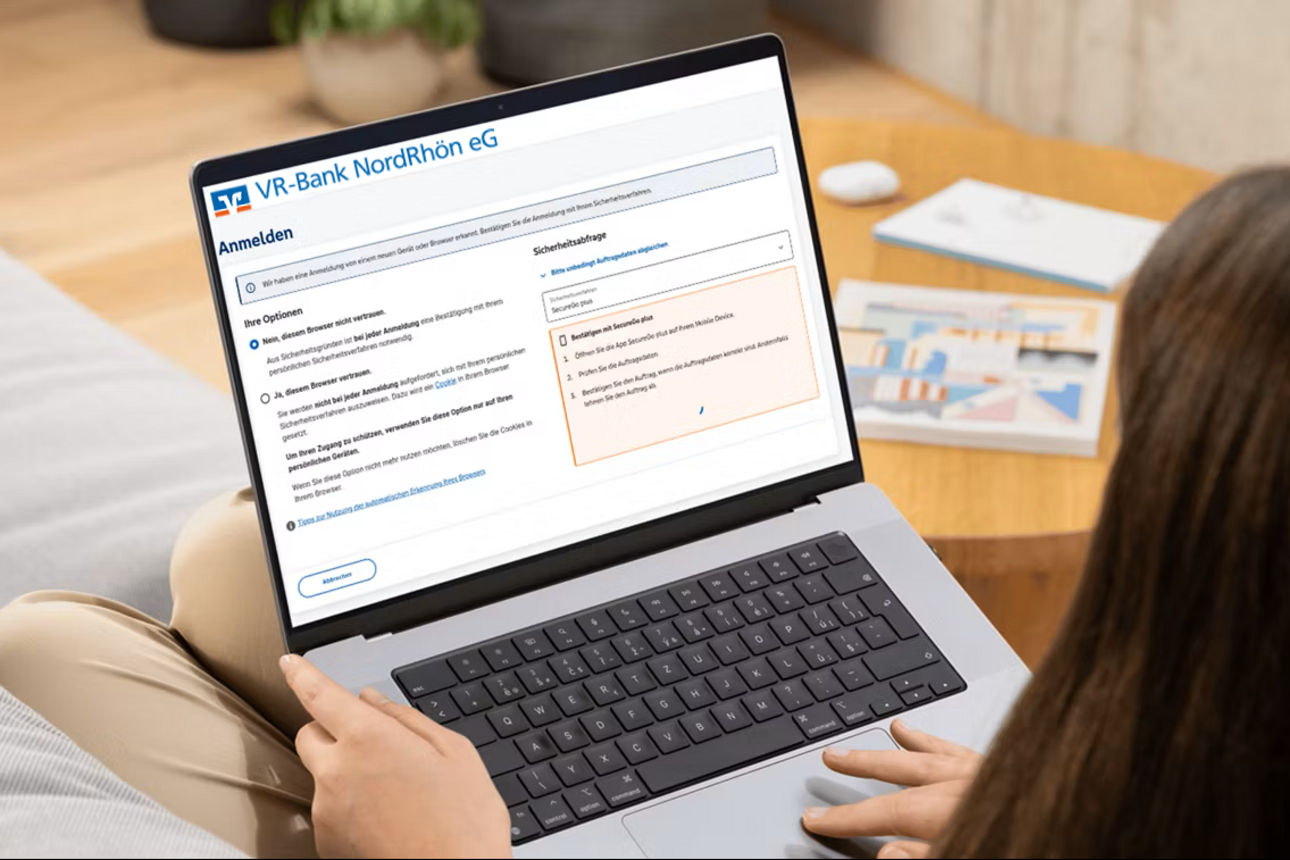 Junge Frau auf dem Sofa schaut auf ihren Laptop