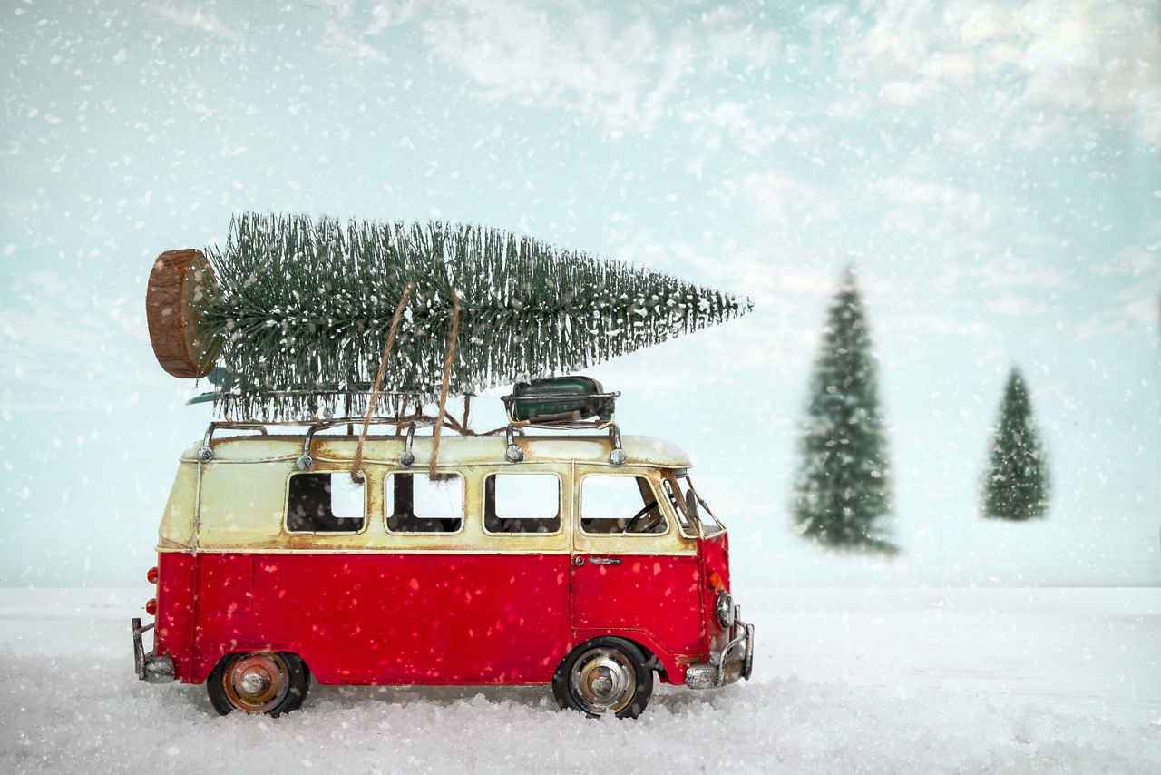Roter Bullie mit Weihnachtsbaum auf dem Dach in Schneelandschaft