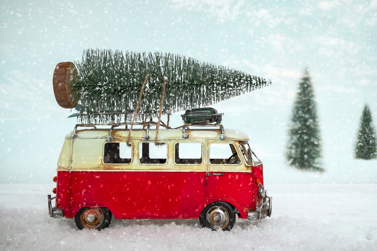Roter Bullie mit Weihnachtsbaum auf dem Dach in Schneelandschaft