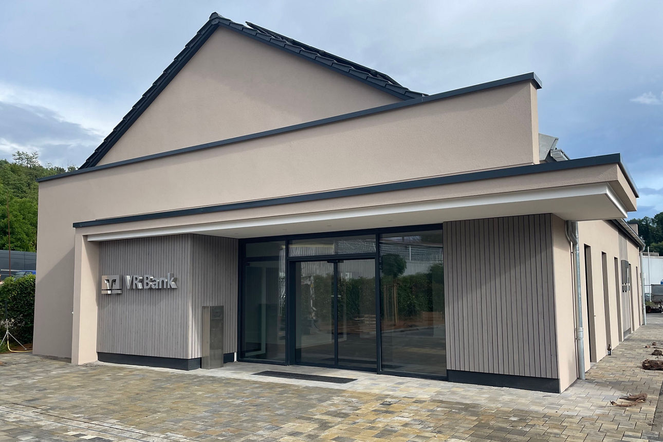 Modernes VR Bank-Gebäude mit Glasfront, davor ein gepflasterter Gehweg.
