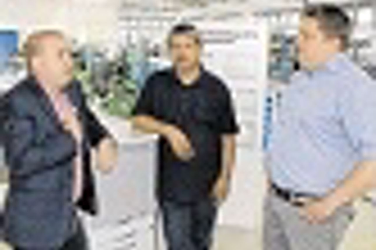 Drei Männer, Geschäftspartner, posieren für die Kamera in einer Fabrikhalle