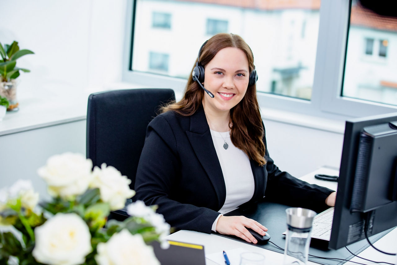 Frau, die ein Headset trägt und in die Kamera lächelt.