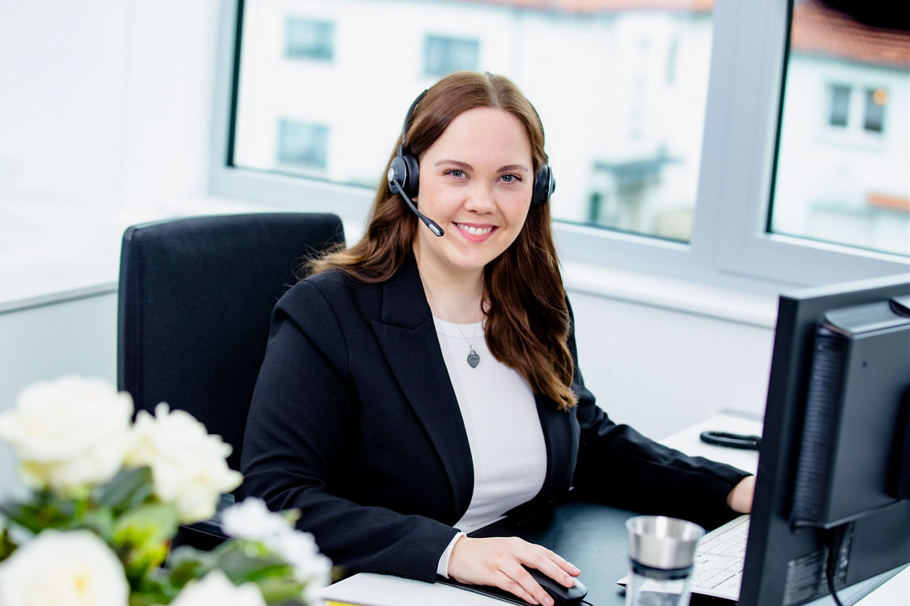 Frau, die ein Headset trägt und in die Kamera lächelt.