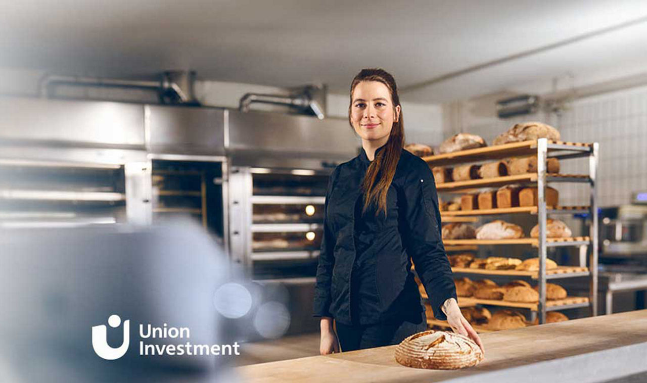Eine junge Frau hat ein frisches Brot gebacken und steht vor ihrer Arbeitsfläche