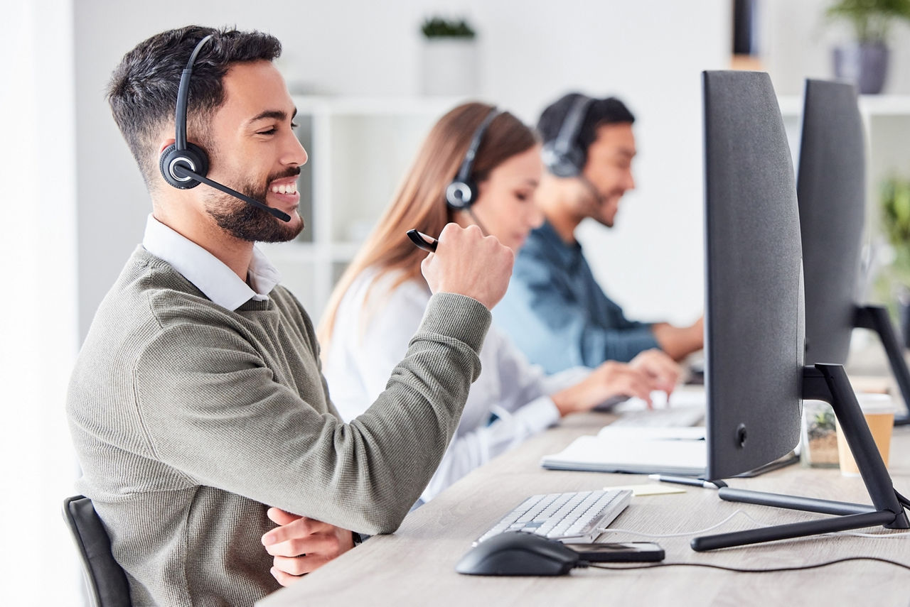 Mitarbeiter eines Callcenters sitzen vor dem Computer
