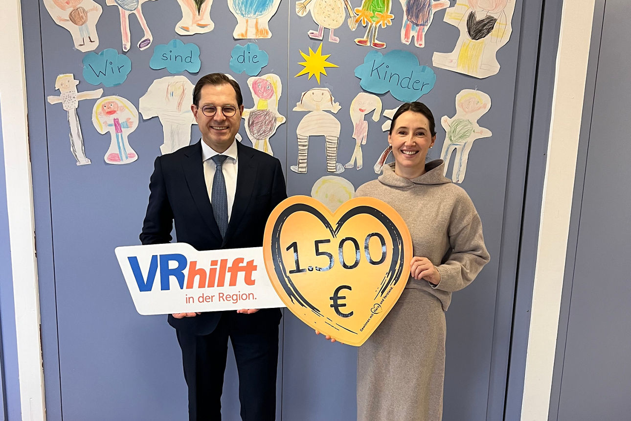 Auf dem Bild stehen der stellvertretender Vorstandsvorsitzende der VR-Bank und eine Frau des Vorstandes des Caritasvereins Sie halten ein Schild in Herzform in den Händen mit Aufschrift der Spendensumme. 