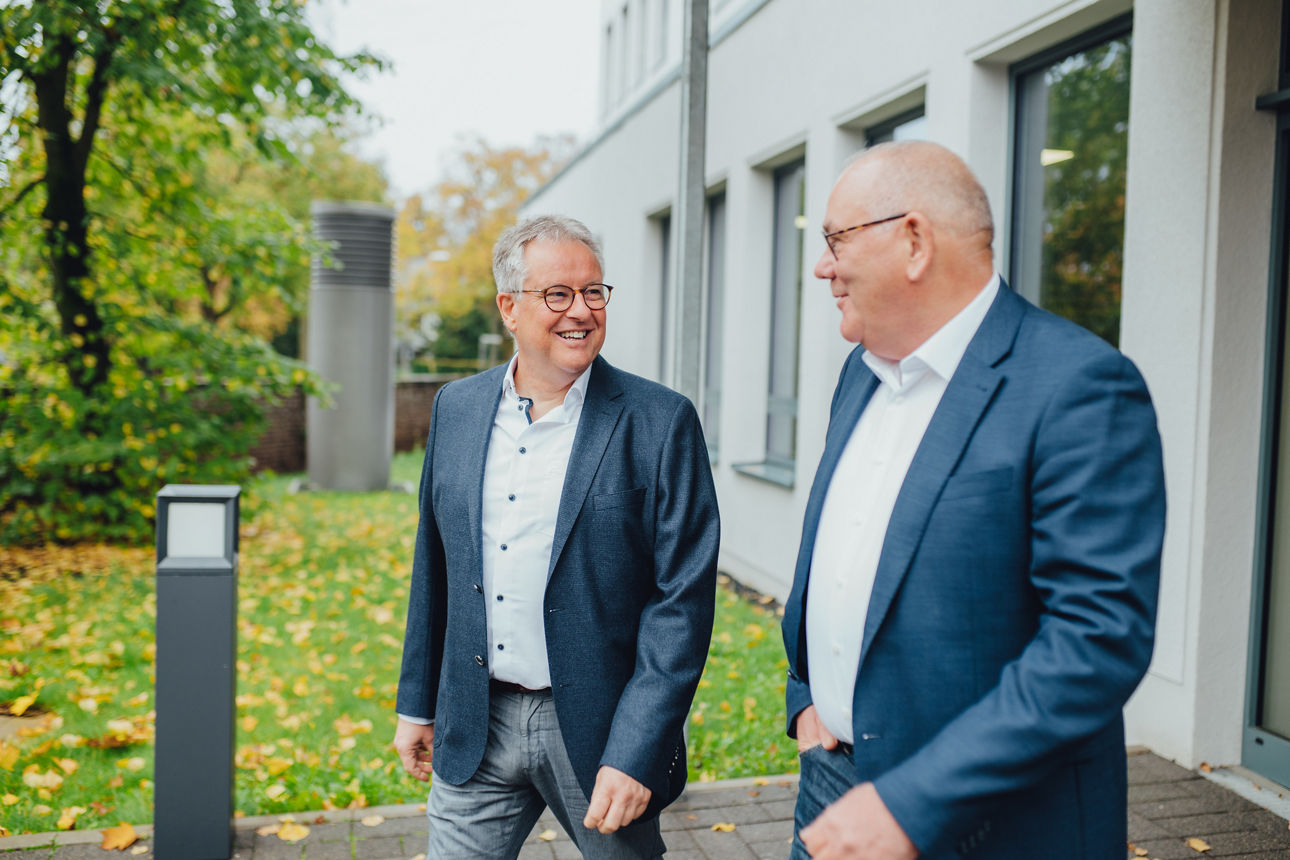 Zwei Männer gehen vor einem Gebäude spazieren