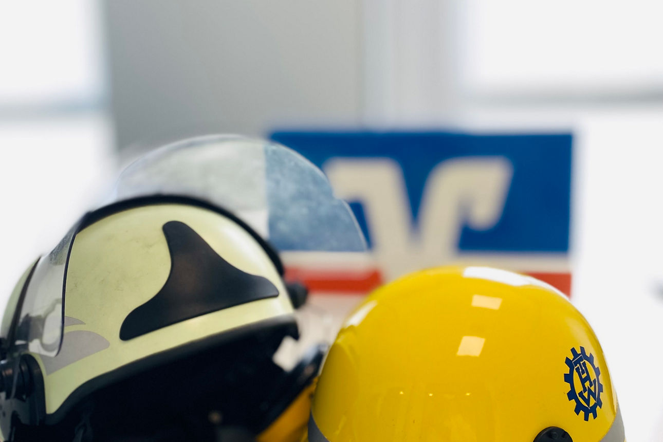 Je ein Helm der Feuerwehr und des THW liegen auf einem Tisch