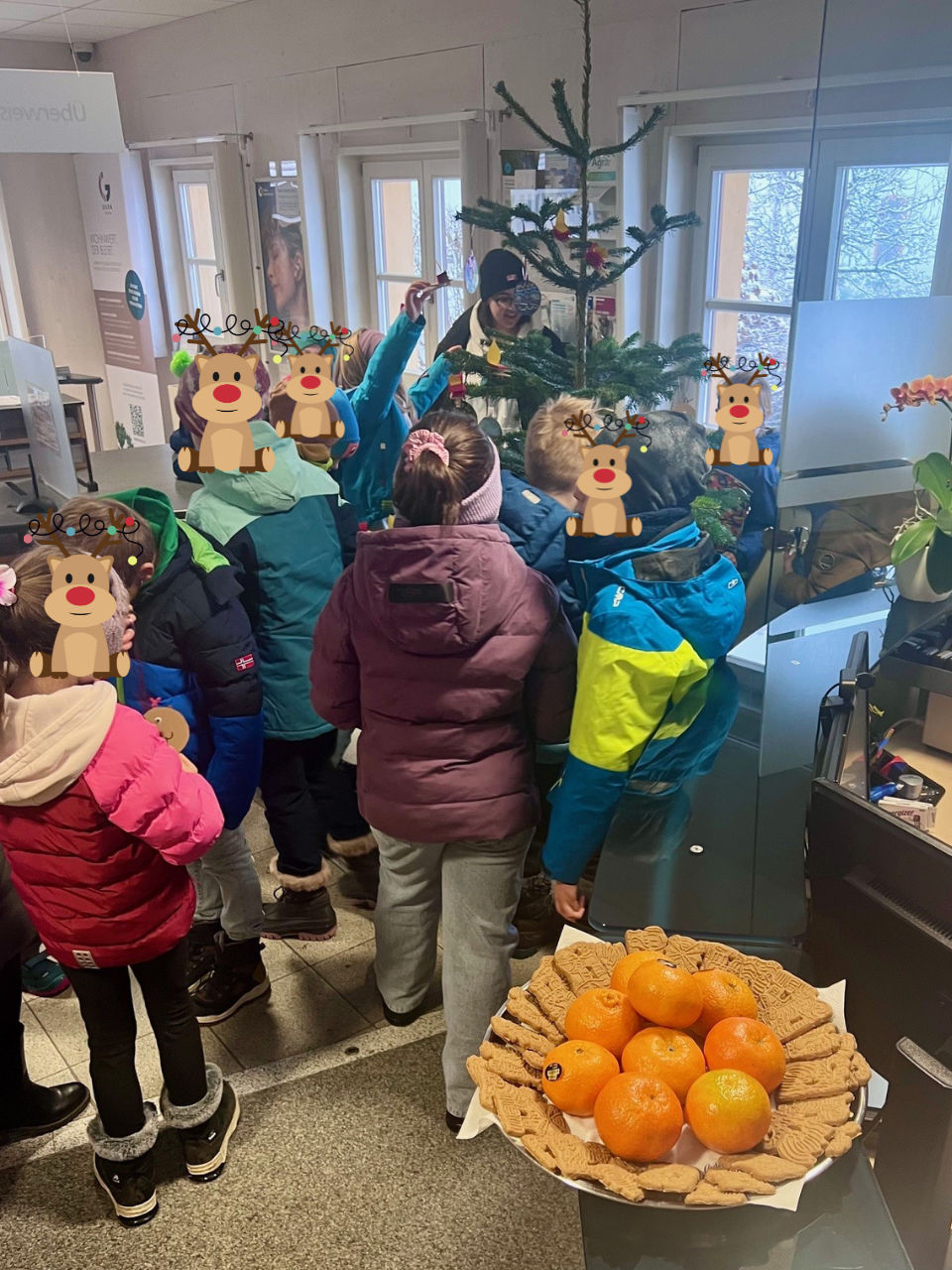Kinder schmücken den Christbaum in der Filiale.