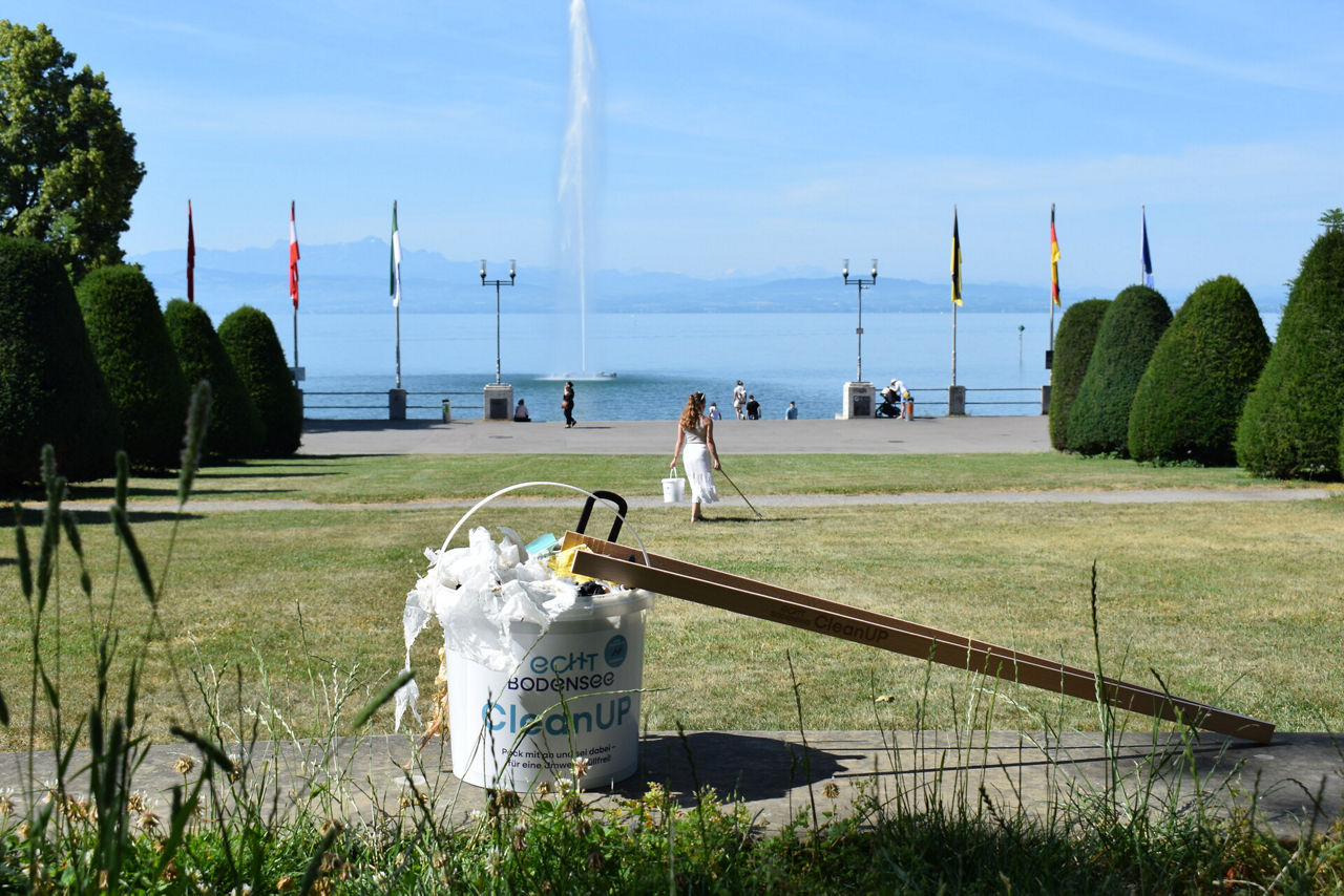 Ein junger Mann sammelt Müll am Bodenseeufer