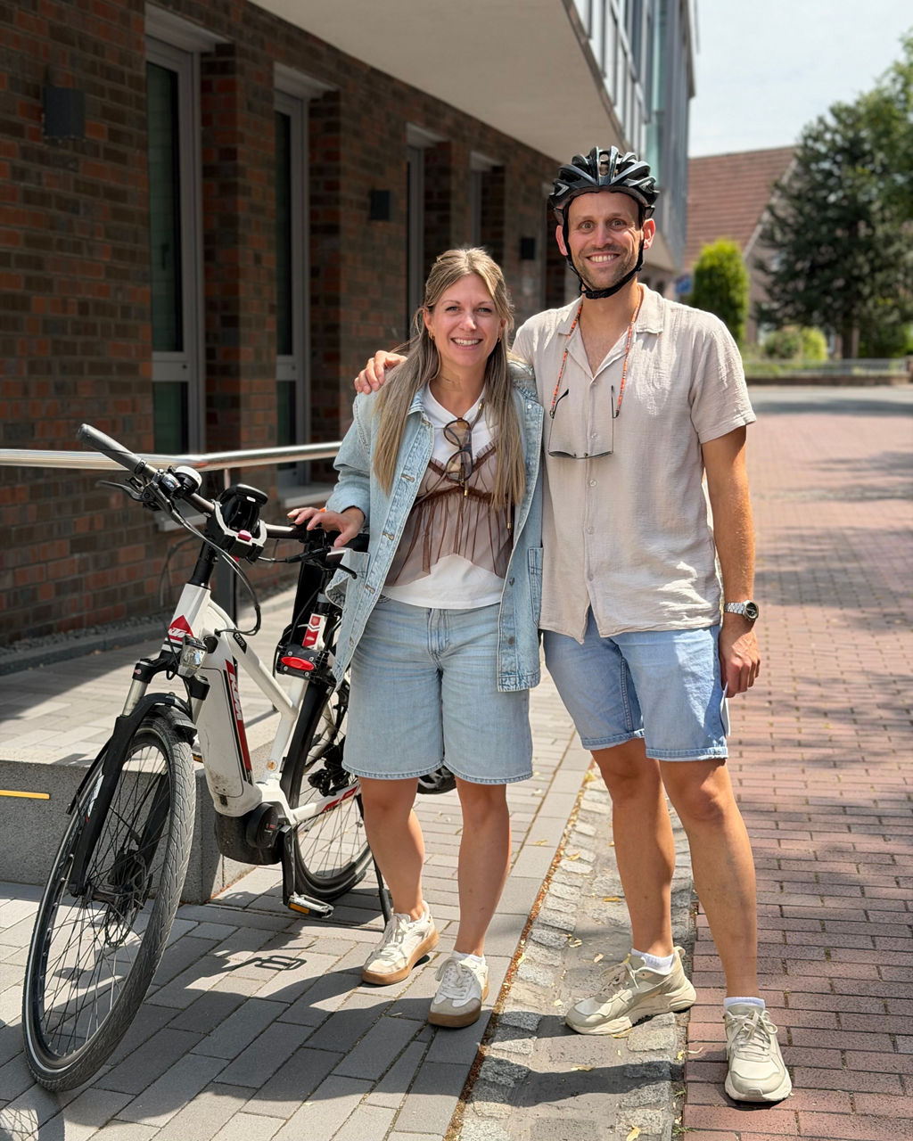Tom Weber und Maren Hegerring aus dem Team von Club50Plus stehen an einem Fahrrad vor der Bank. 