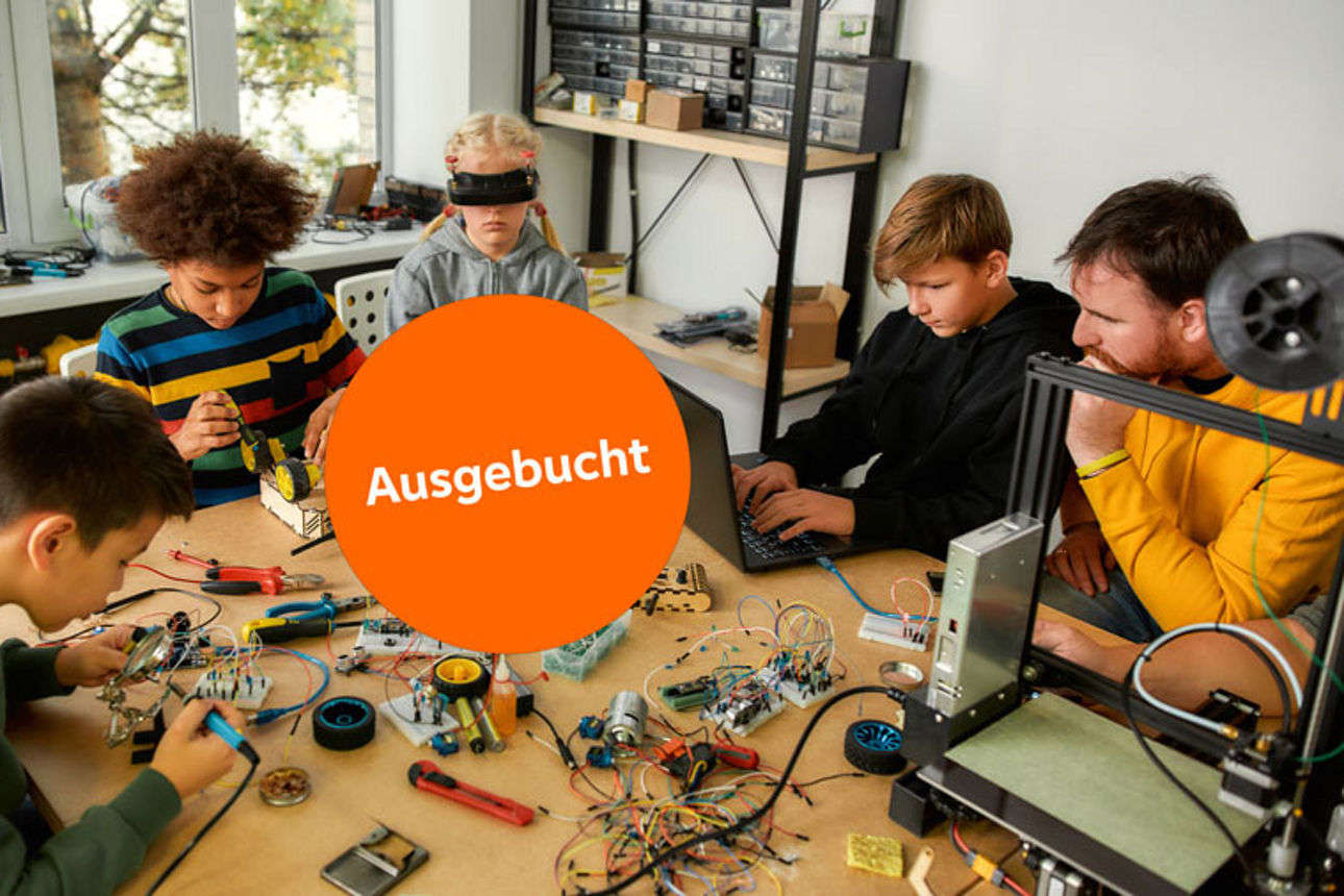 Kinder sitzen an Tisch und tüfteln