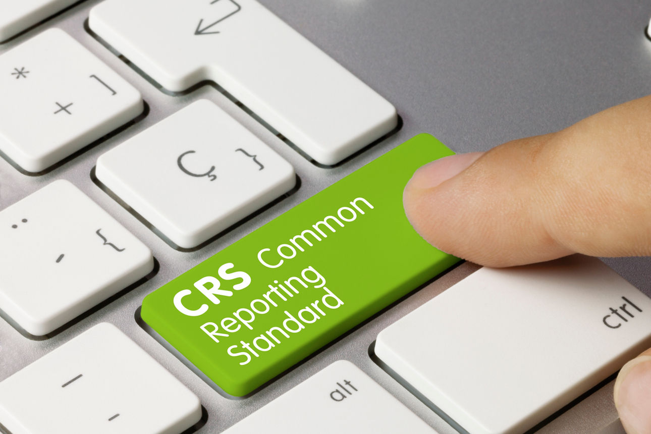 Ausschnitt einer Tastatur mit großer grüner Taste, deren Beschriftung Common Reporting Standard ausweist.