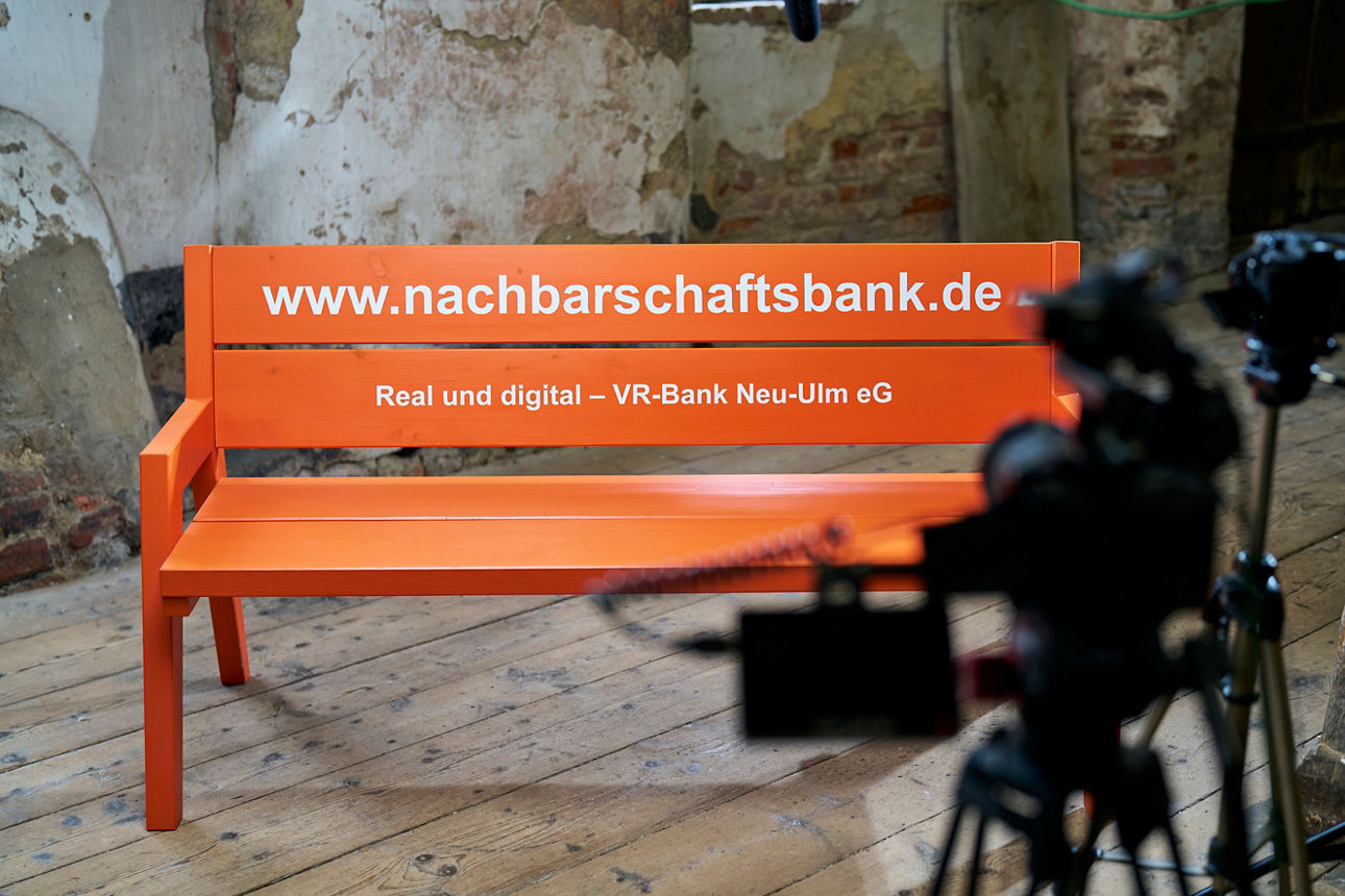 Die orangene Nachbarschaftsbank wird von einer Kamera gefilmt