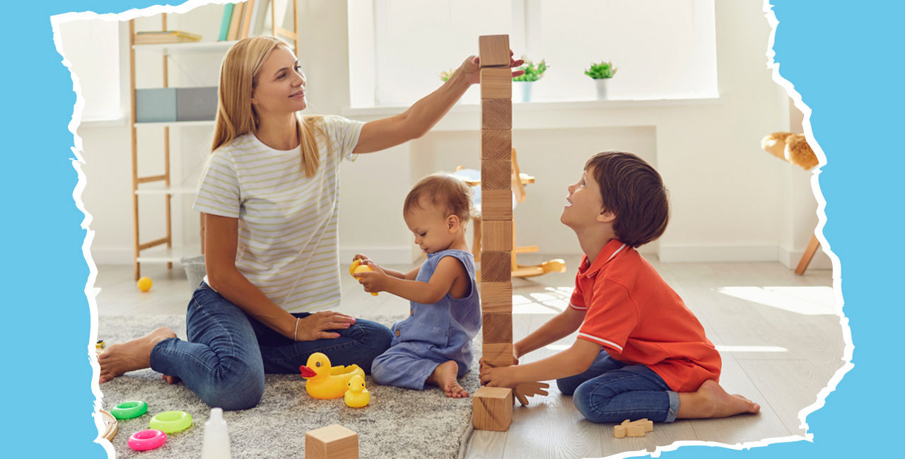 Eine Frau spielt mit 2 kleinen Kindern. Sie bauen ein Turm auf