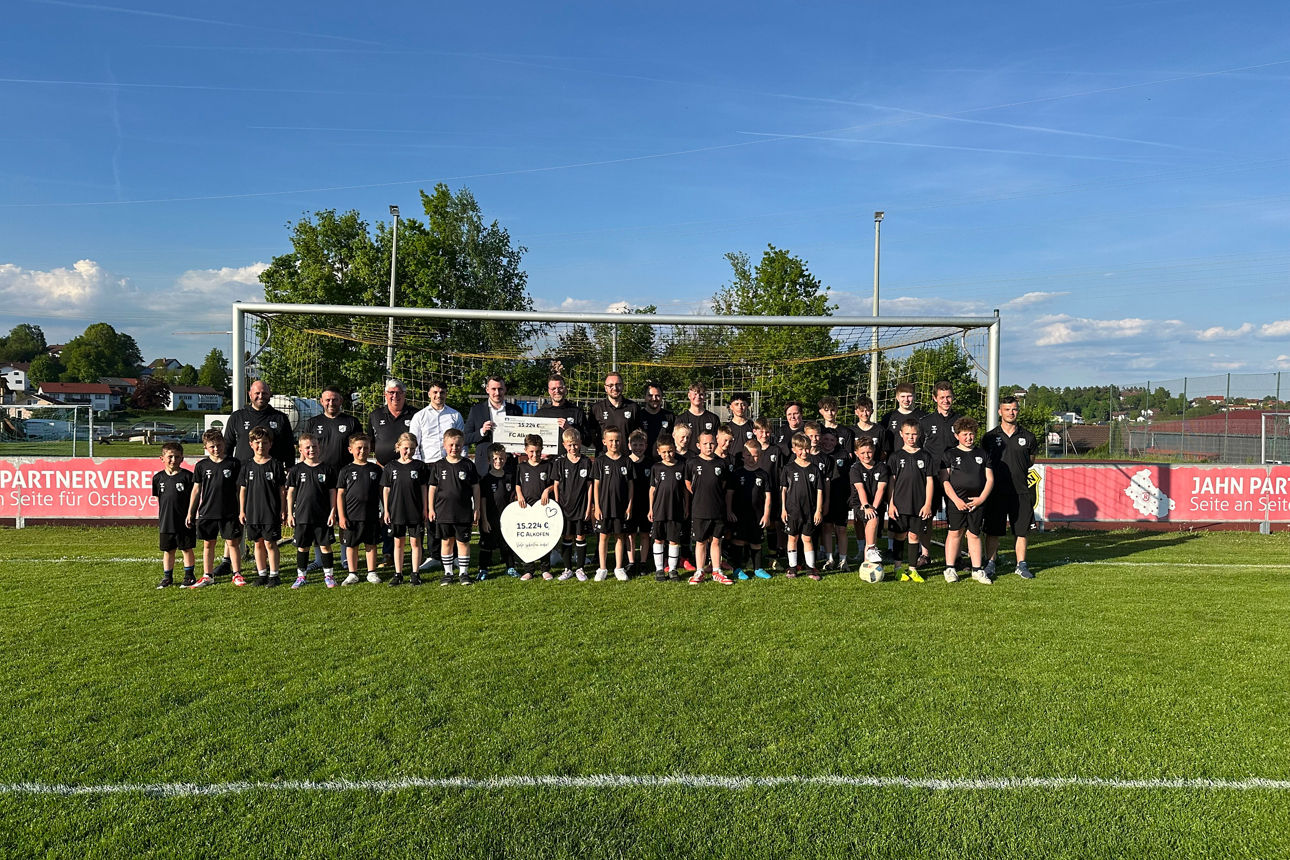 FC Alkofen mit Mitarbeitern der Bank und Spendenscheck auf dem Fussballplatz