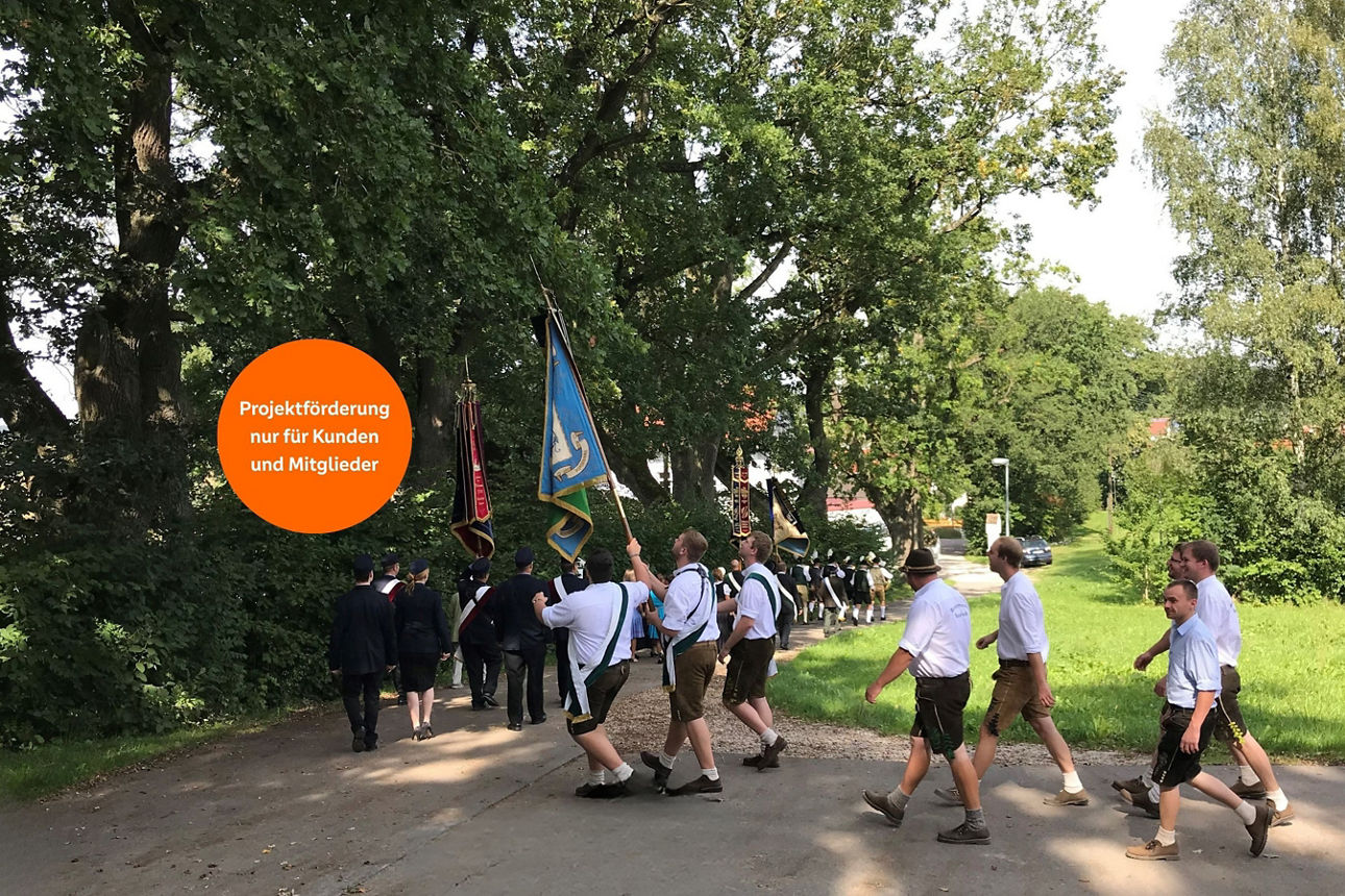 Verschiedene Männer in bayrischer Tracht marschieren mit ihren Fahnen