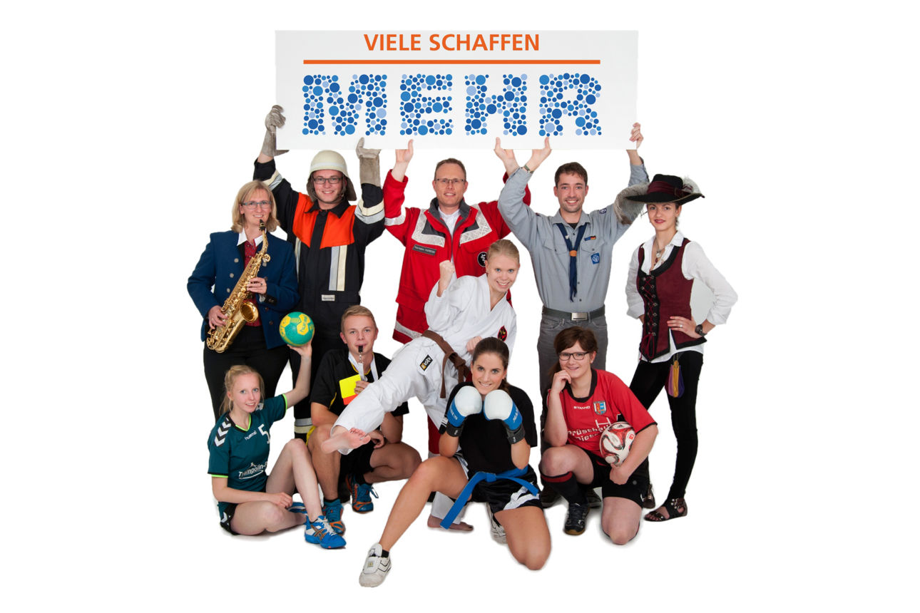 Personengruppe mit unterschiedlichen Vereinsmitgliedern halten ein „Viele schaffen mehr“-Logo in die Höhe