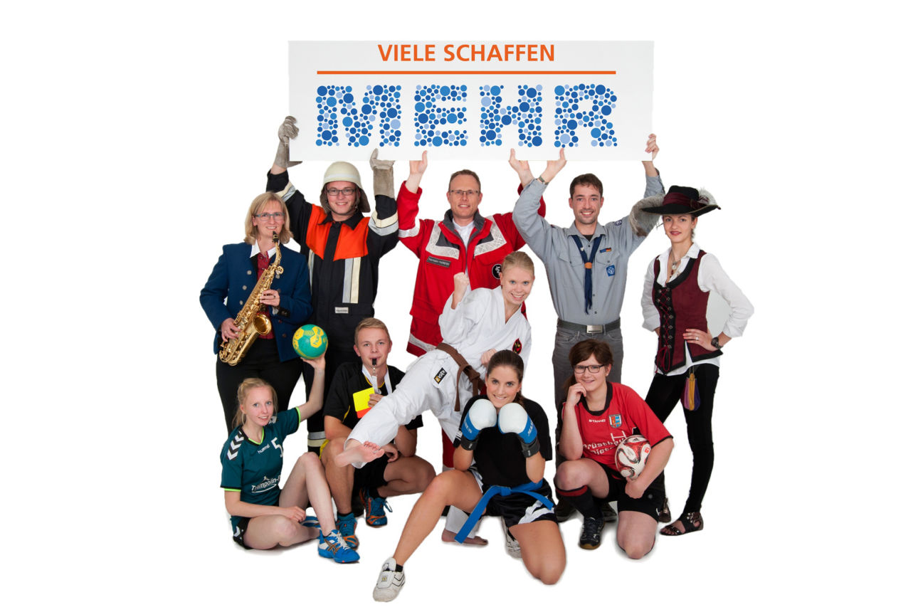 Personengruppe mit unterschiedlichen Vereinsmitgliedern halten ein „Viele schaffen mehr“-Logo in die Höhe