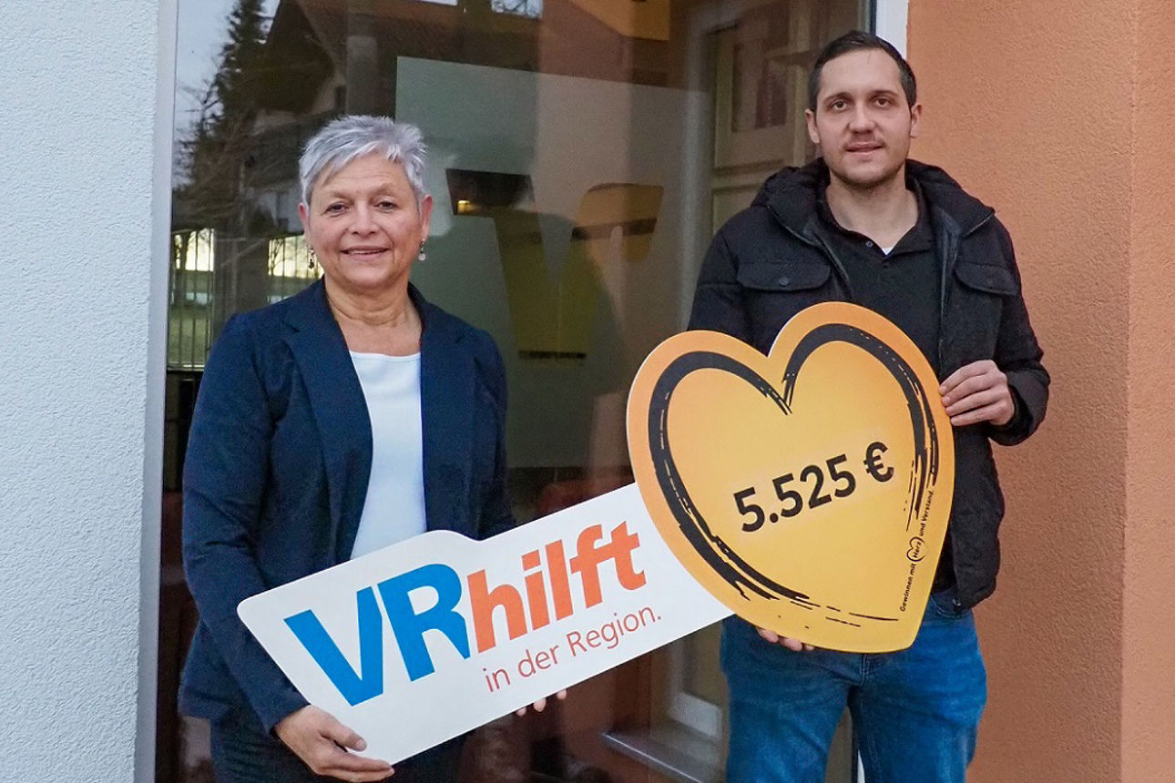 Eine Kollegin hält zusammen mit einem Vertreter eines begünstigten Vereins den Spendenscheck in der Hand