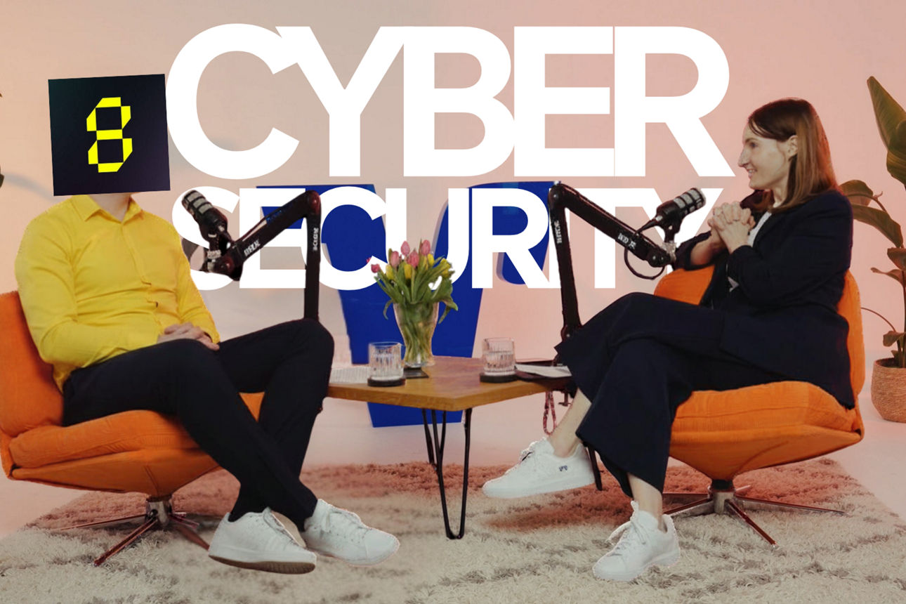 Zwei Personen sitzen sich mit Mikrofonen in einem Podcast-Studio gegenüber, im Hintergrund steht „CyberSecurity“.