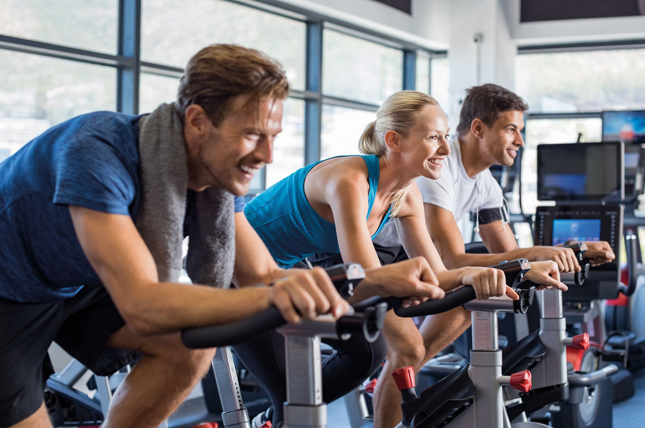 Zwei Männer und eine Frau beim Indoor Cycling