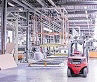 Blick ins Innere einer großen Fabrikhalle mit einem roten Gabelstapler auf der rechten Seite