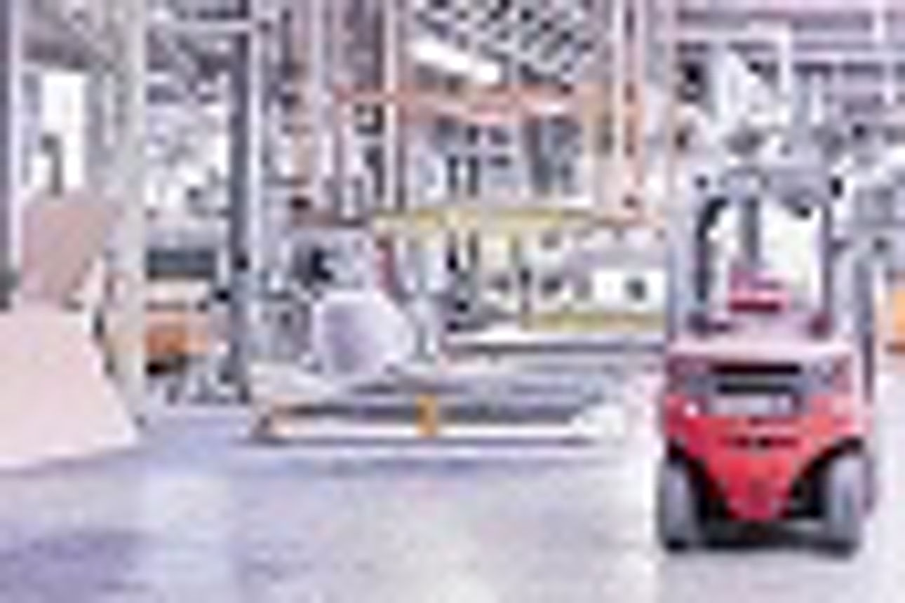 Blick ins Innere einer großen Fabrikhalle mit einem roten Gabelstapler auf der rechten Seite