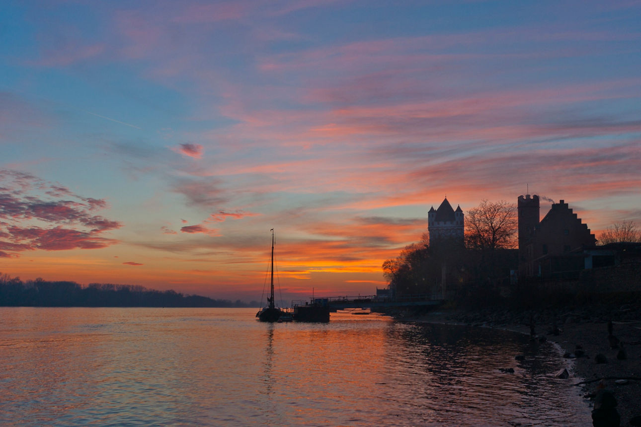 Sonnenuntergang bei Eltville am Rhein - im Vordergrund eine Burg und ein Segelboot