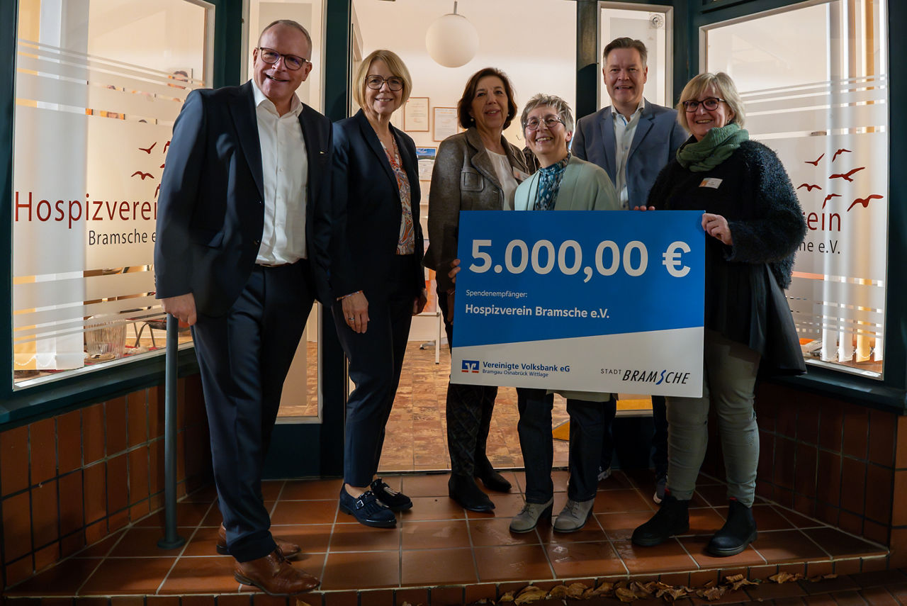 6 Personen halten einen Scheck über die Spende von 5000€ vor sich