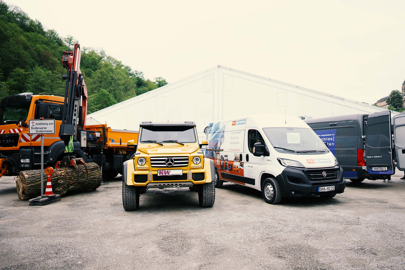 Ein Lkw, Mercedes Truck und Van stehen vor einem großen Zelt. Dabei steht auch ein Baustellenfahrzeug, das beim Aufbau der Job Messe geholfen hat.