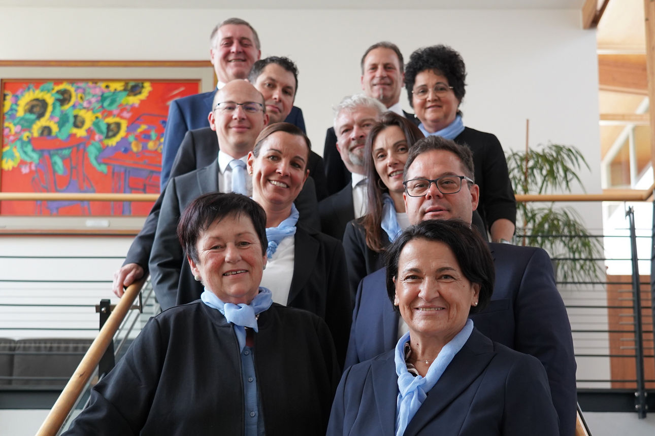 Frauen und Männer in Anzügen auf einer Treppe, die in die Kamera lächeln