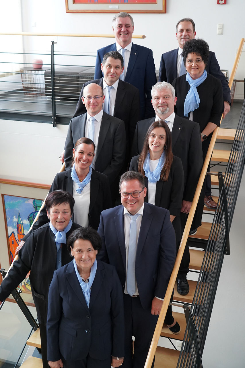 Frauen und Männer in Anzügen auf einer Treppe, die in die Kamera lächeln
