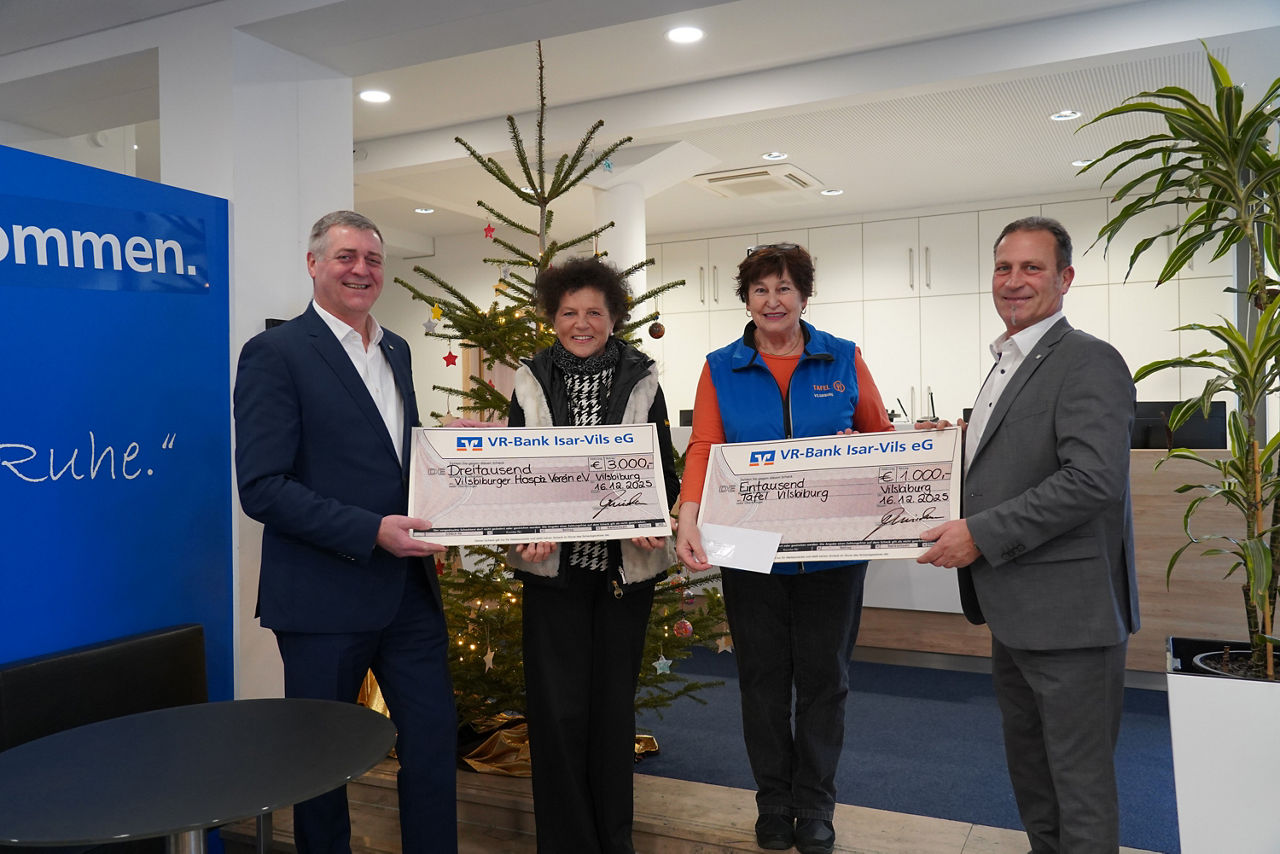 Zwei Männer und zwei Frauen lächeln mit Spendenschecks in der Hand in die Kamera