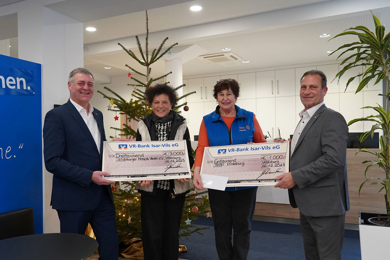 Zwei Männer und zwei Frauen lächeln mit Spendenschecks in der Hand in die Kamera