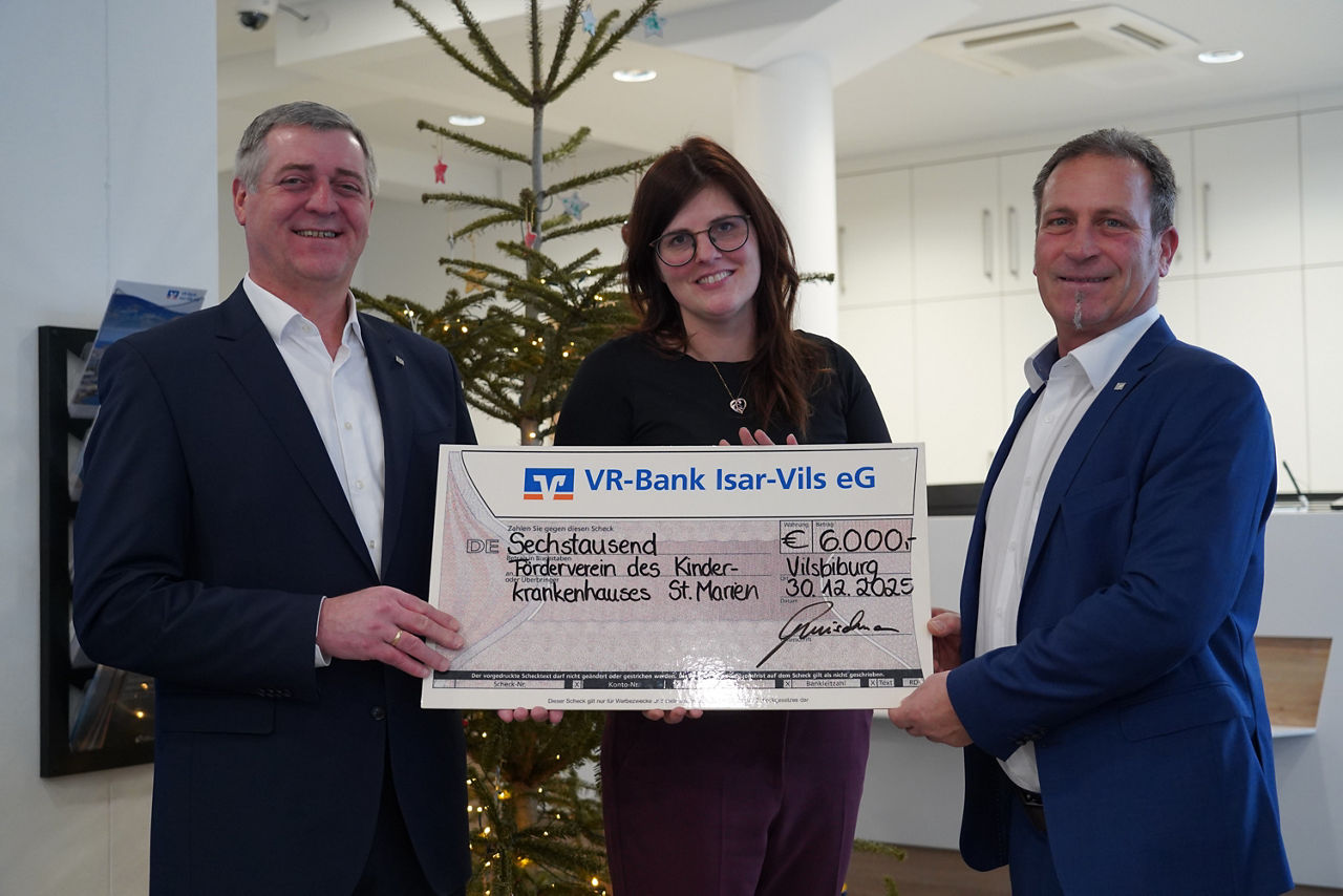 Zwei Männer und eine Frau lächeln mit einem Spendenscheck in die Kamera.