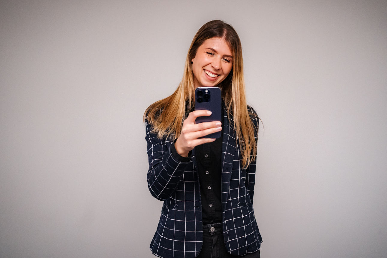 Frau in Casual Business Outfit mit Handy in der Hand
