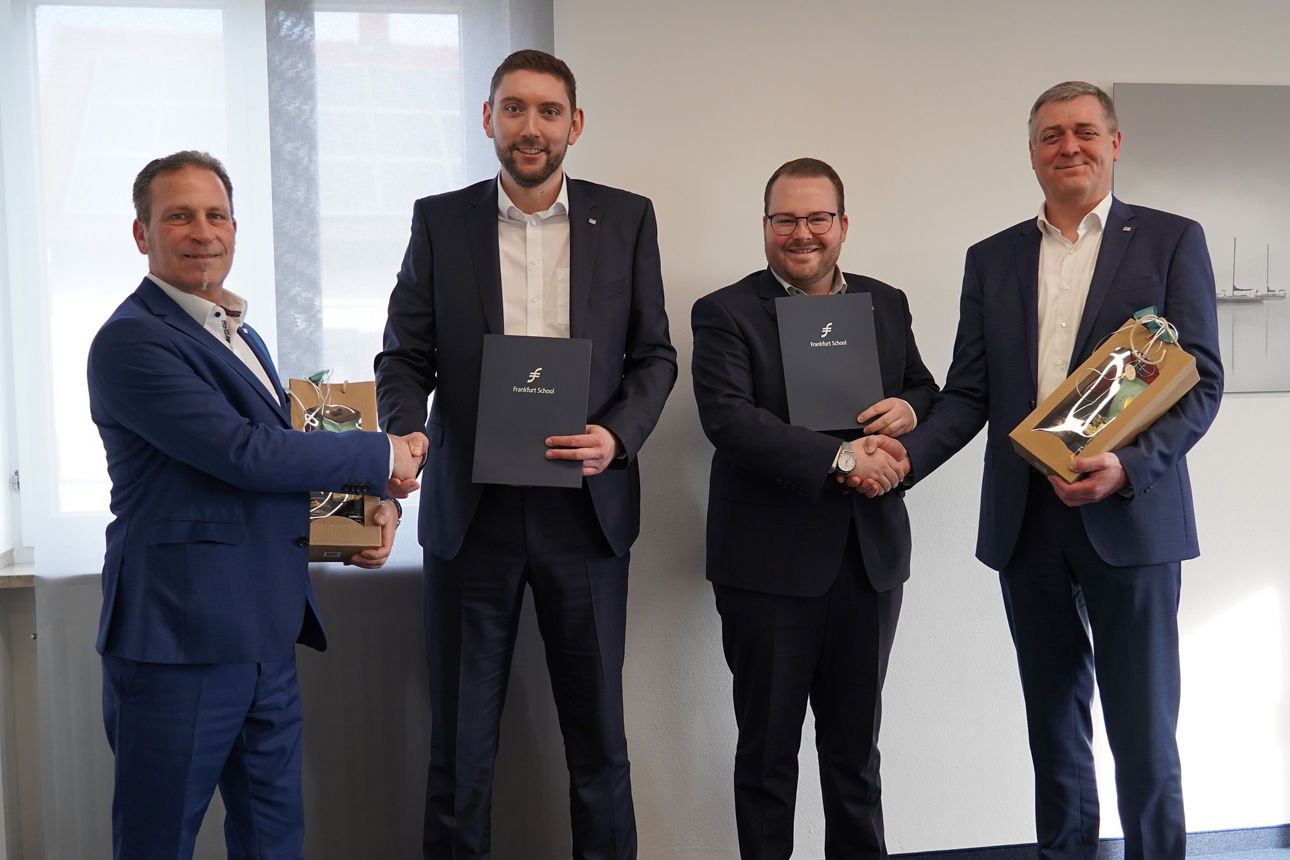 Vier Männer in Anzügen reichen sich die Hände