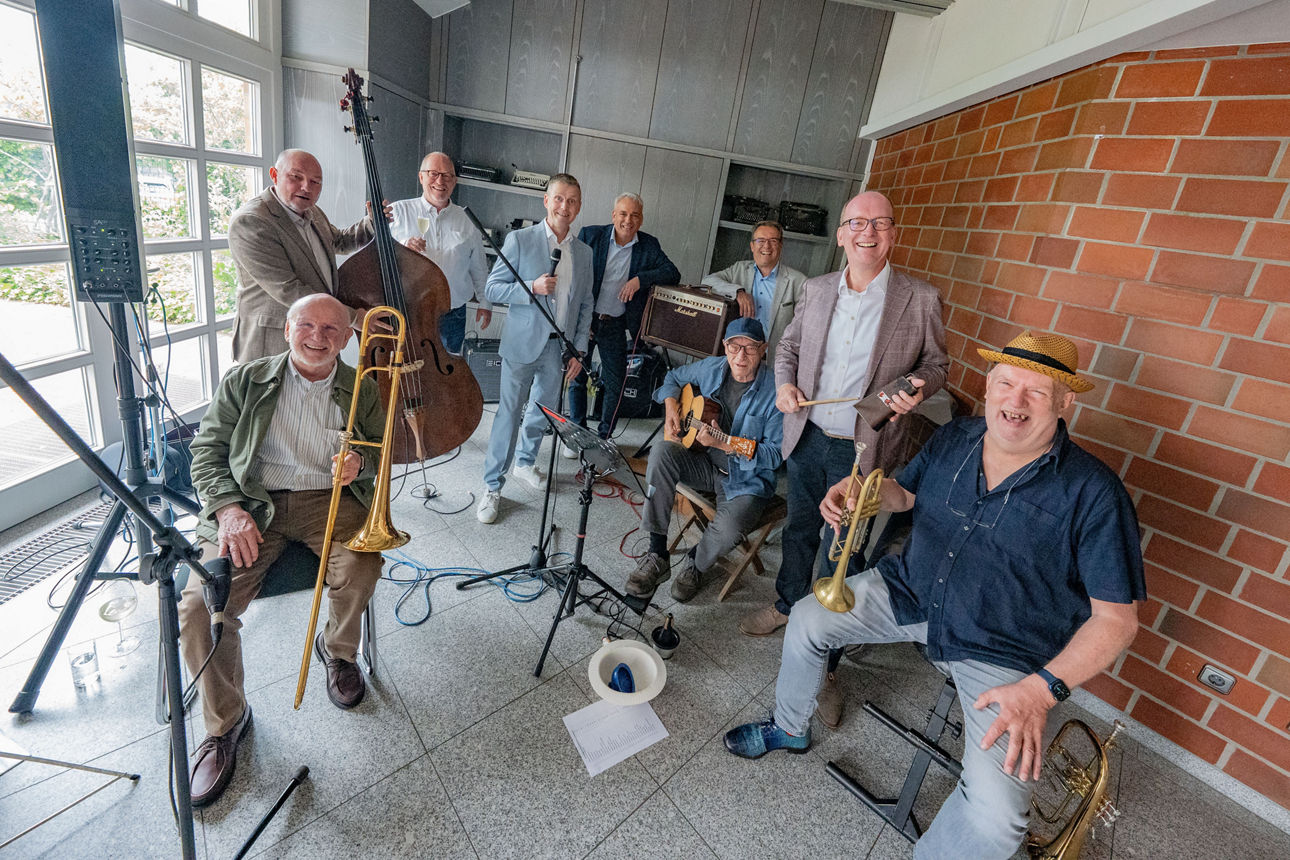 Auf dem Foto stehen eine Band mit Instrumenten und Mitarbeitende der Volksbank im Bankgebäude und lächeln in die Kamera.