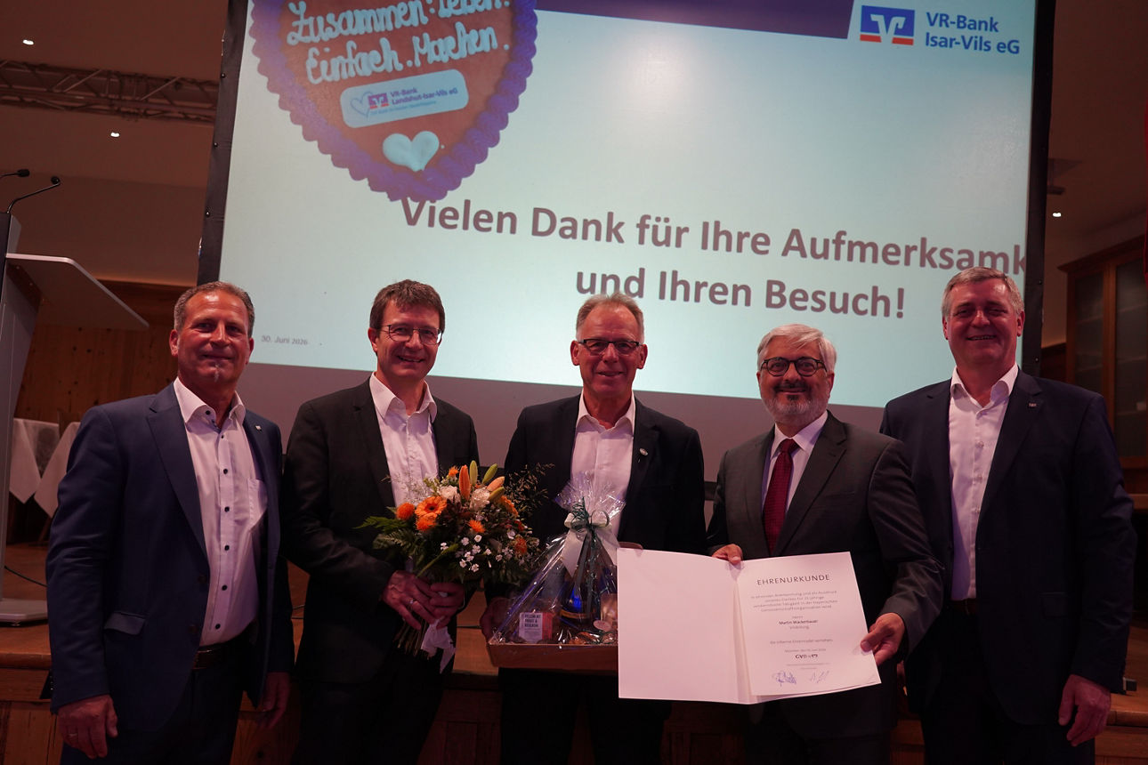 Eine Gruppe von Männern in Anzügen stehen vor einer großen Leinwand und lächeln in die Kamera