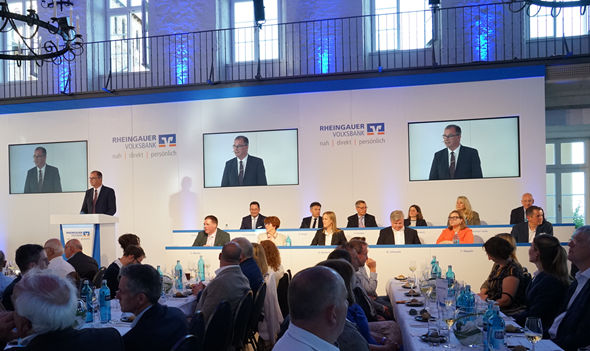 Mann hält Rede auf Podium bei Veranstaltung der Rheingauer Volksbank, Publikum sitzt an gedeckten Tischen in festlichem Saal