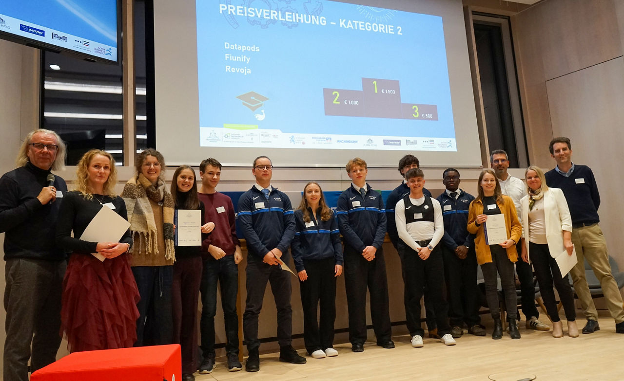 Die Studenten stehen in einer Reihe mit einer Urkunde zur Kategorie "Beste Idee aus den Schulen/Hochschulen"