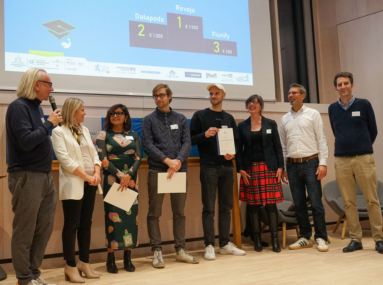 Die Studenten stehen in einer Reihe mit einer Urkunde zur Kategorie "Beste Idee aus den Schulen/Hochschulen"