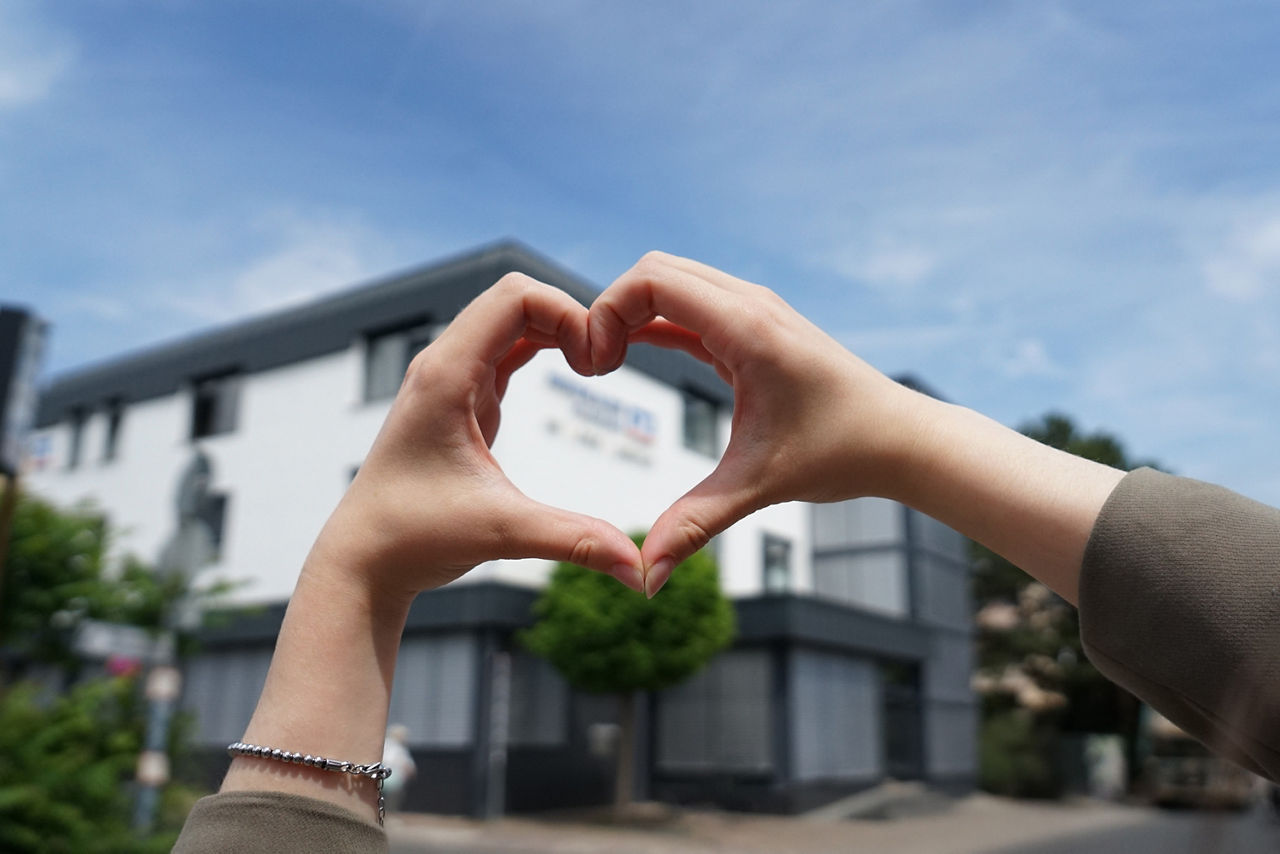 Hände zum Herz geformt - im Hintergrund Hauptstelle der Rheingauer Volksbank in Geisenheim