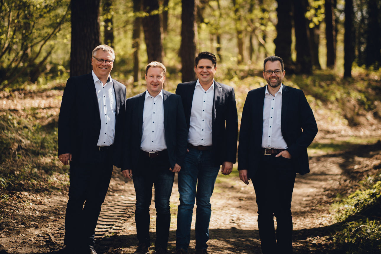 Zwei Personen stehen auf dem Feld. Im Hintergrund ist ein Landwirtschaftsmaschine