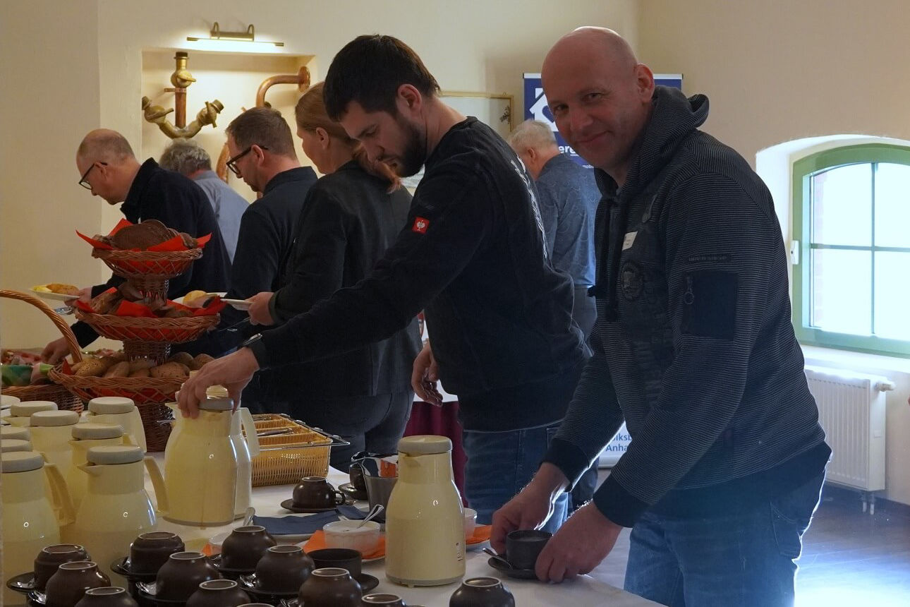 Mehrere gutgelaunte Menschen am Früchstücksbuffet