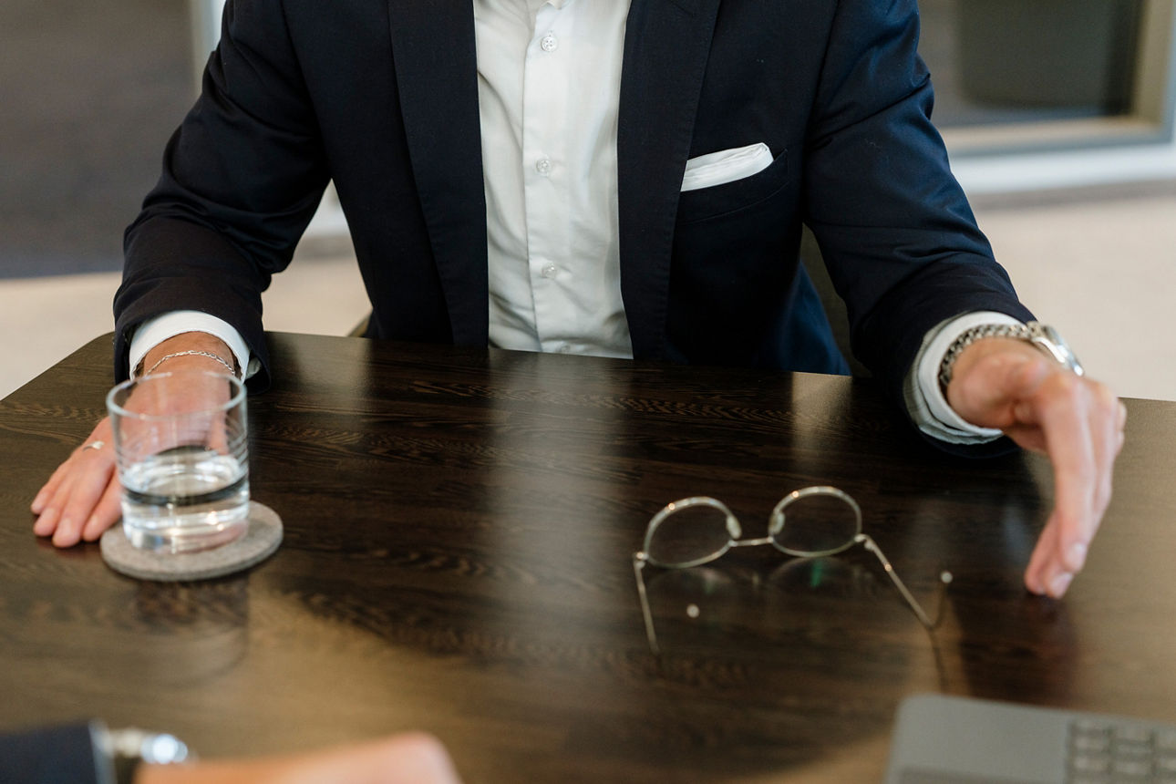 Eine Person in Business-Kleidung sitzt an einem Konferenztisch und erklärt etwas