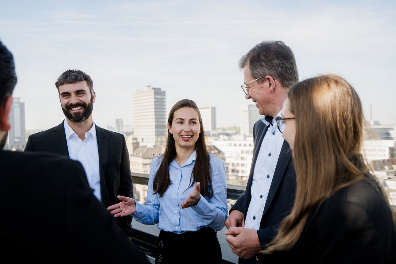 Mehrere Personen unterhalten sich im Freien auf einer Dachterrasse